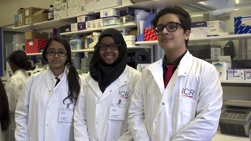 Three students in lab coats in cancer lab