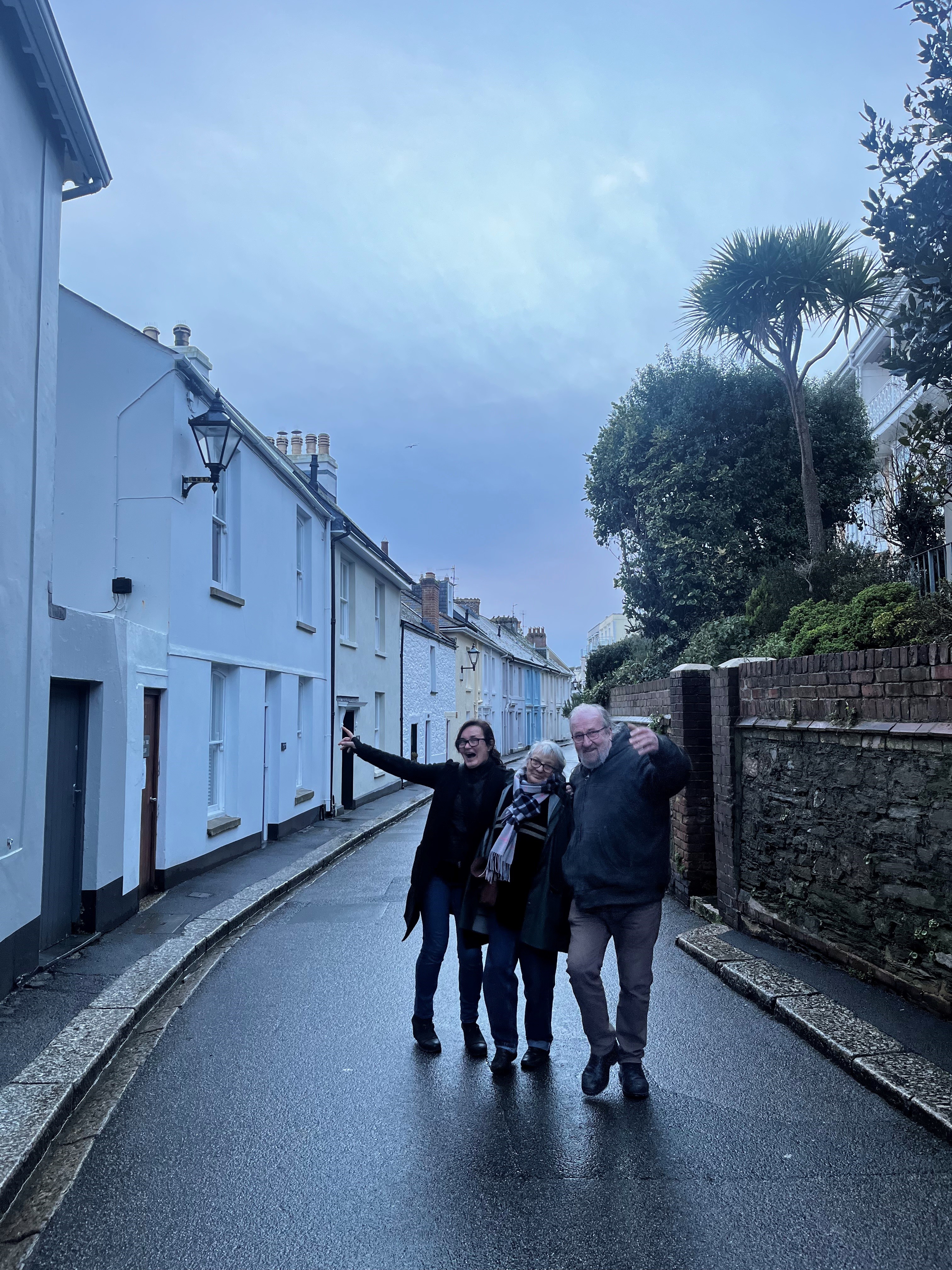 Ally and her parents pose for the camera in a street lined with houses on one side