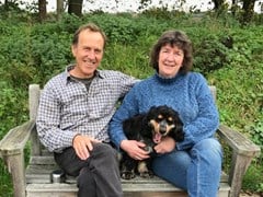 Camilla Keeling and her husband David sitting on a bench outdoors with their dog