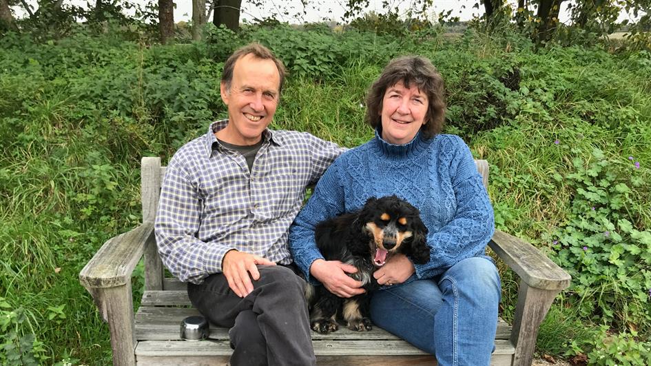 Camilla Keeling and her husband David sitting on a bench outdoors with their dog