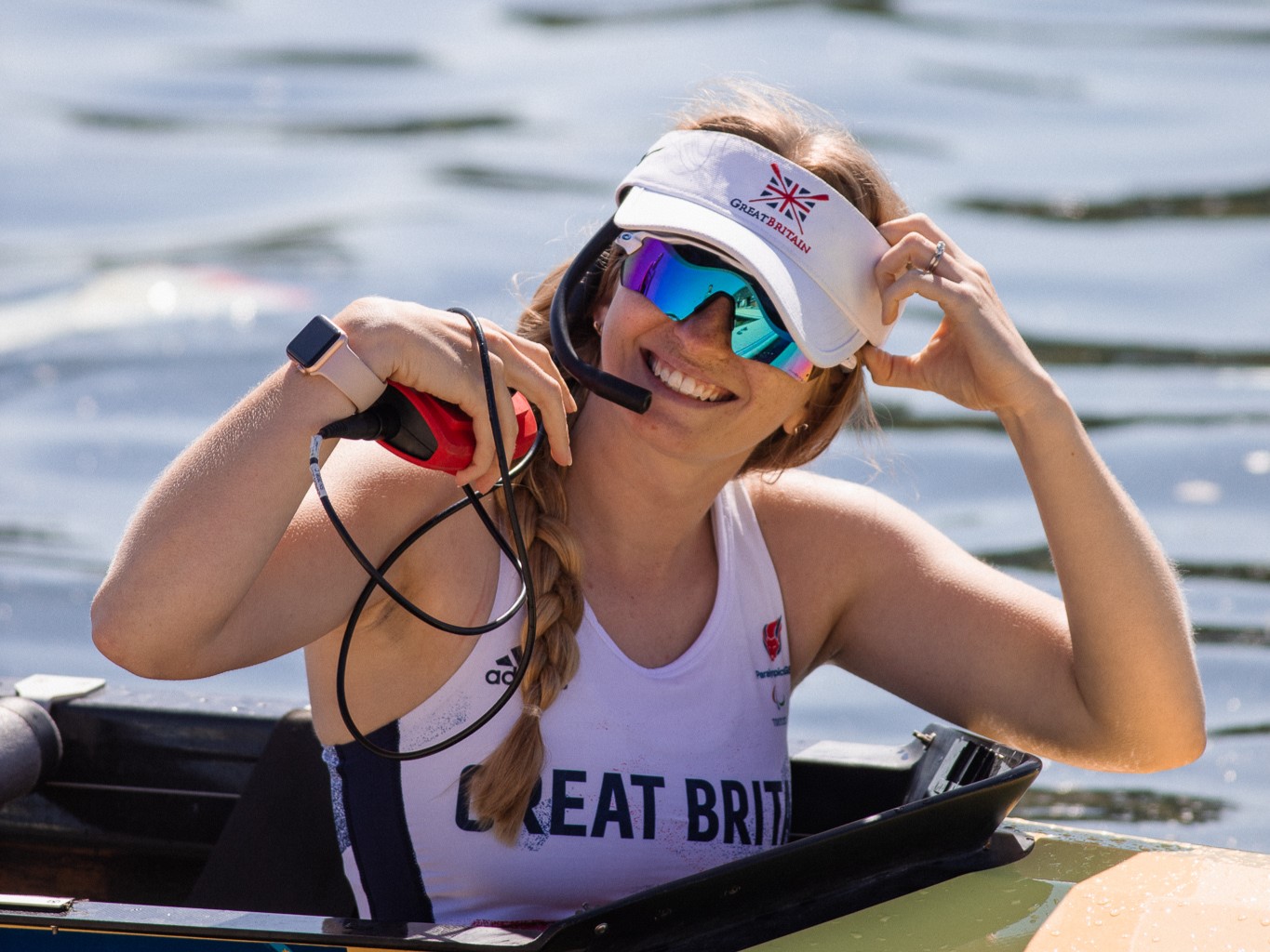 A smiling Erin in a boat wears a white Great Britain cap and white GB t shirt ands sunglasses
