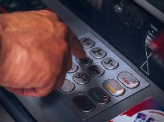 Hand typing bank code at ATM