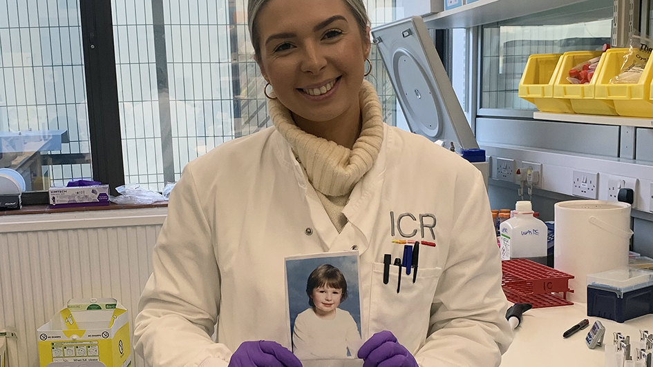 Isabel Nichols in the lab holding up a printed picture of herself as a kid