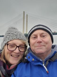 Selfie of sally Wells, a patient on the trial and her husband in front of a bridge on a cold day