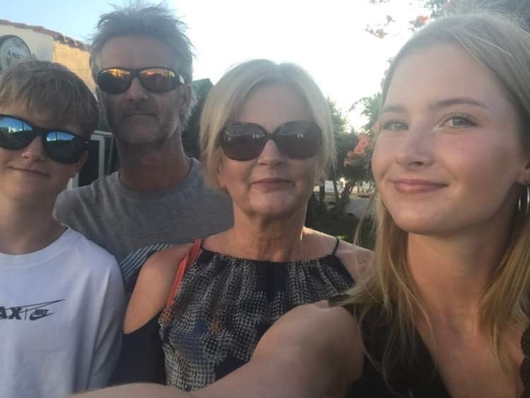 Mark's son, Mark and his wife - all wearing sunglasses stand next to his daughter who is taking a selfie of them all