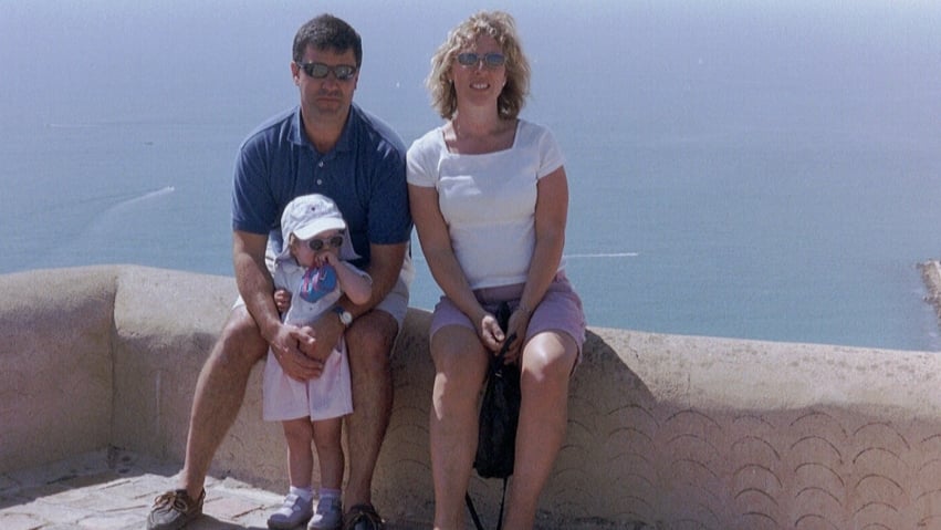 Mike and Liz sat on a wall in front of the sea with Abbie stood in front of them