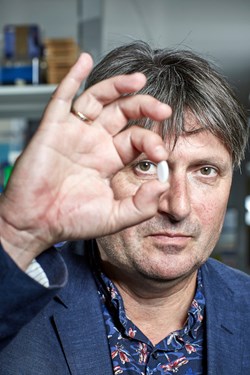 Poet Laureate Simon Armitage holding pill with engraved poem