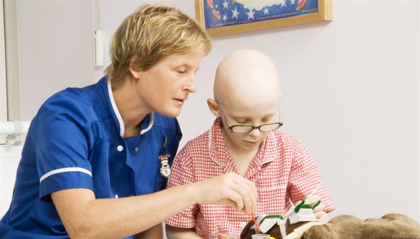 Staff nurse playing with a young boy in hospital. He is undergoing treatment for a childhood cancer. 