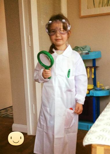 Ines is a young girl dressed in a white lab coat and goggles